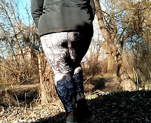 Plumper Mummy with phat bootie in stretch pants peeing outdoors while standing doggie-style